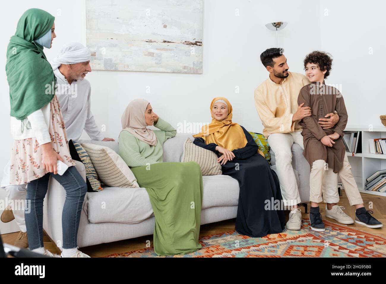 young arabian man hugging son near multicultural muslim family at home Stock Photo