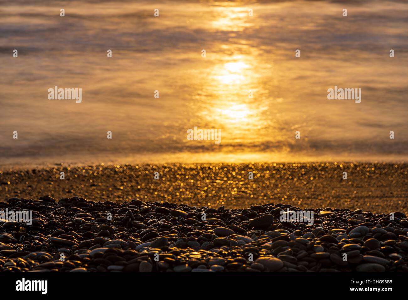 Early morning sun reflecting on the sea and stony beach at Tajao, Tenerife, Canary Islands, Spain Stock Photo