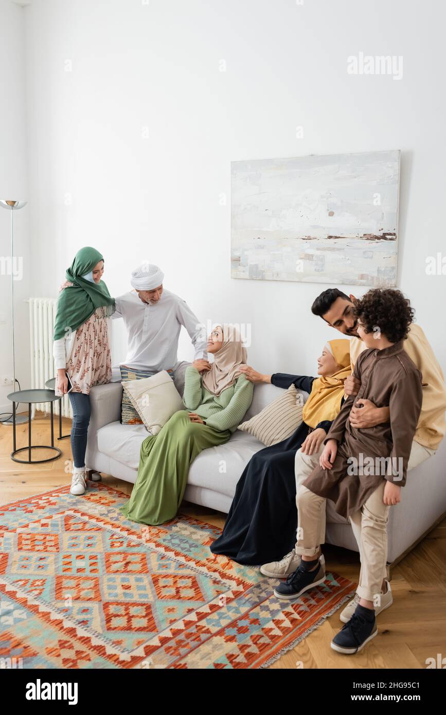 young muslim man hugging arabian son near cheerful multicultural family in living room Stock Photo