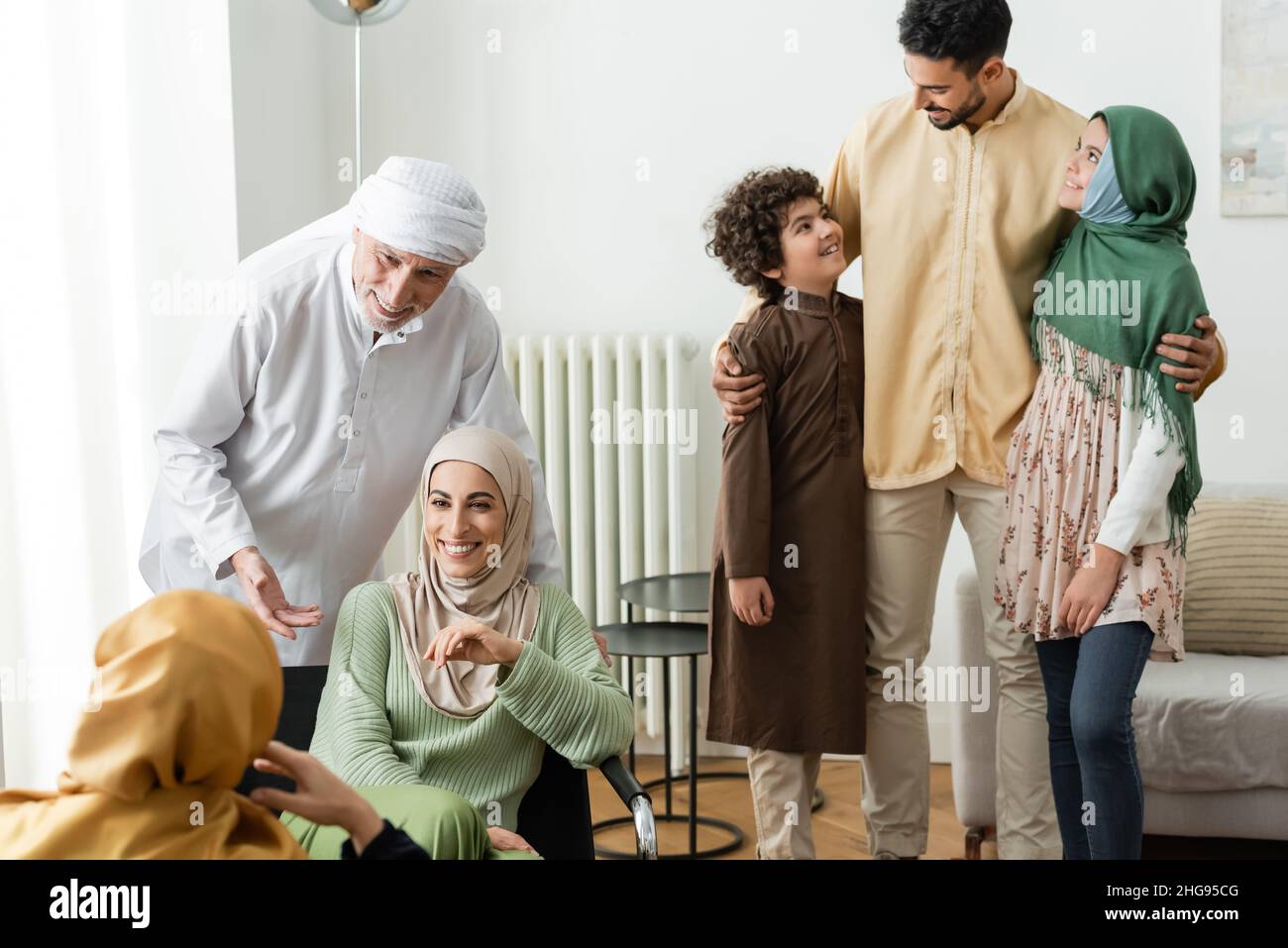 arabian man hugging interracial kids near muslim family at home Stock Photo