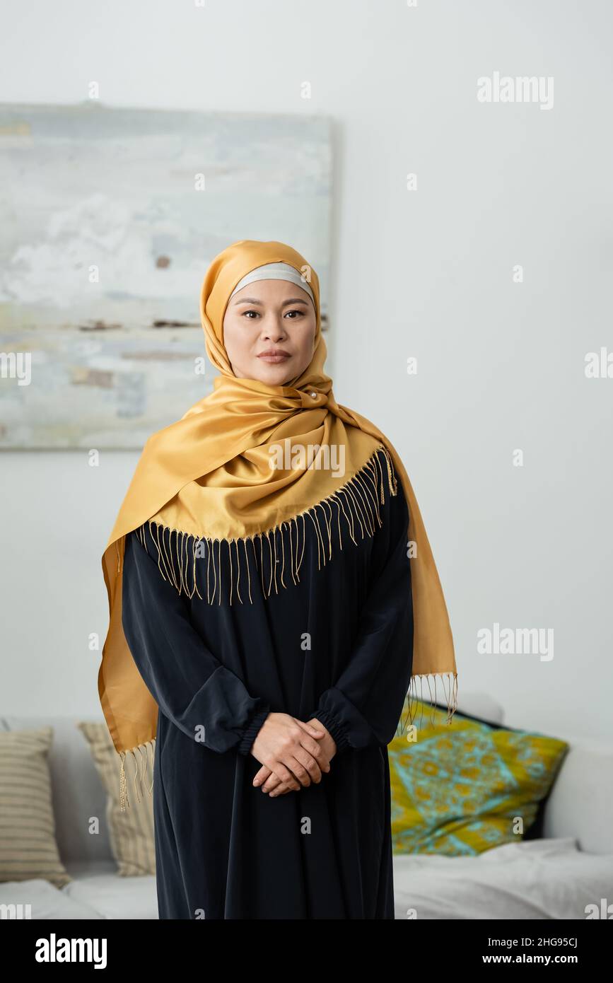 middle aged asian woman in hijab looking at camera at home Stock Photo