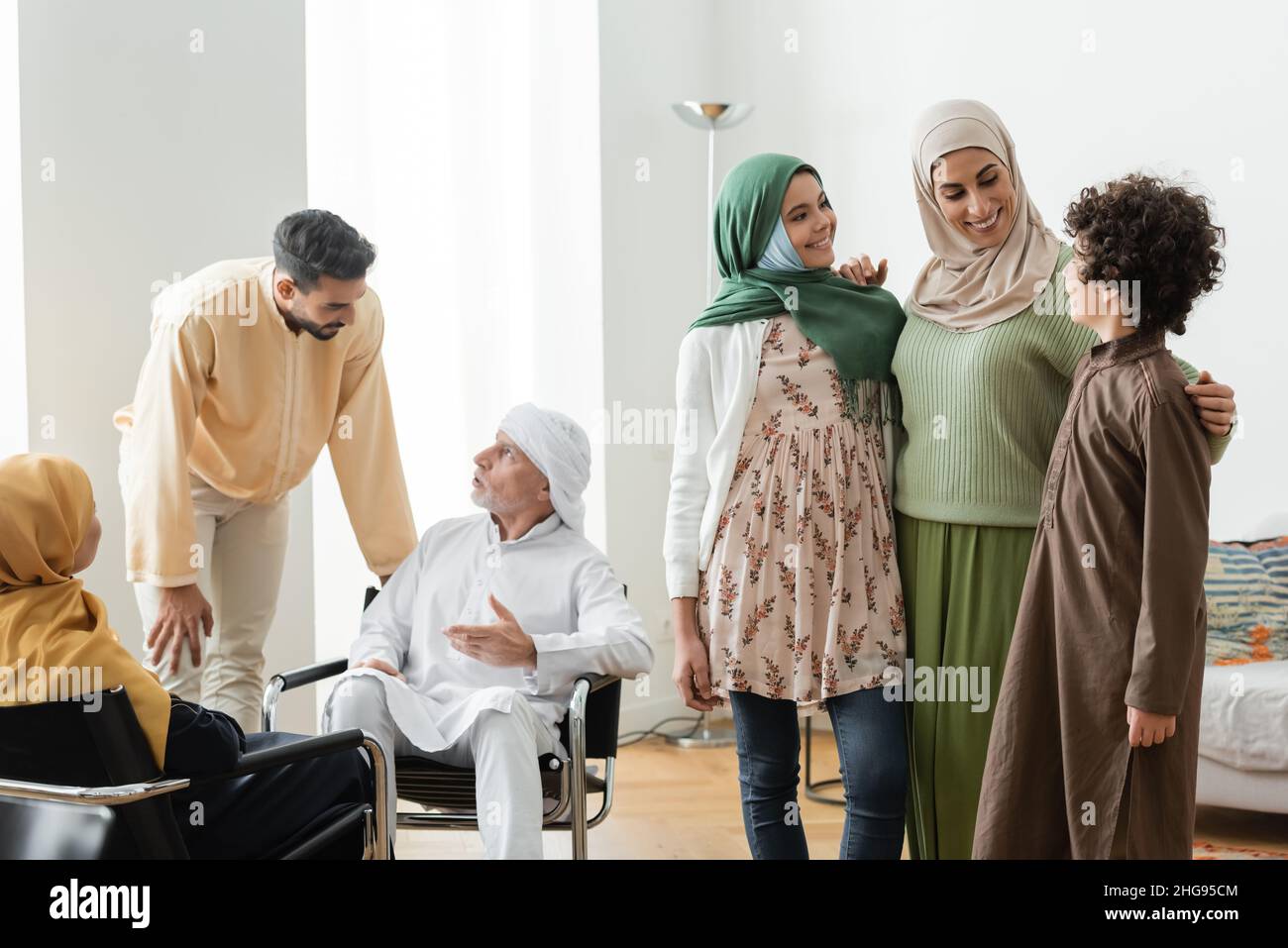 mature man talking to adult son near multiethnic muslim family at home Stock Photo