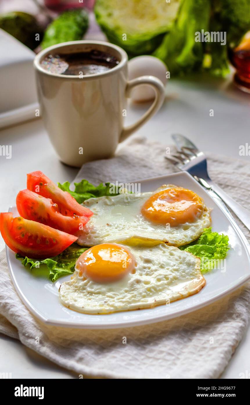 Fried eggs from two eggs on a plate with tomato Stock Photo