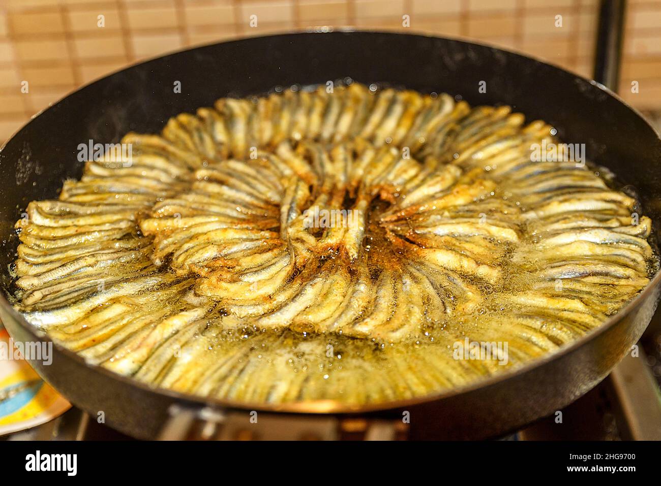 Anchovy fish carefully lined up in a large pan are fried at home Stock Photo