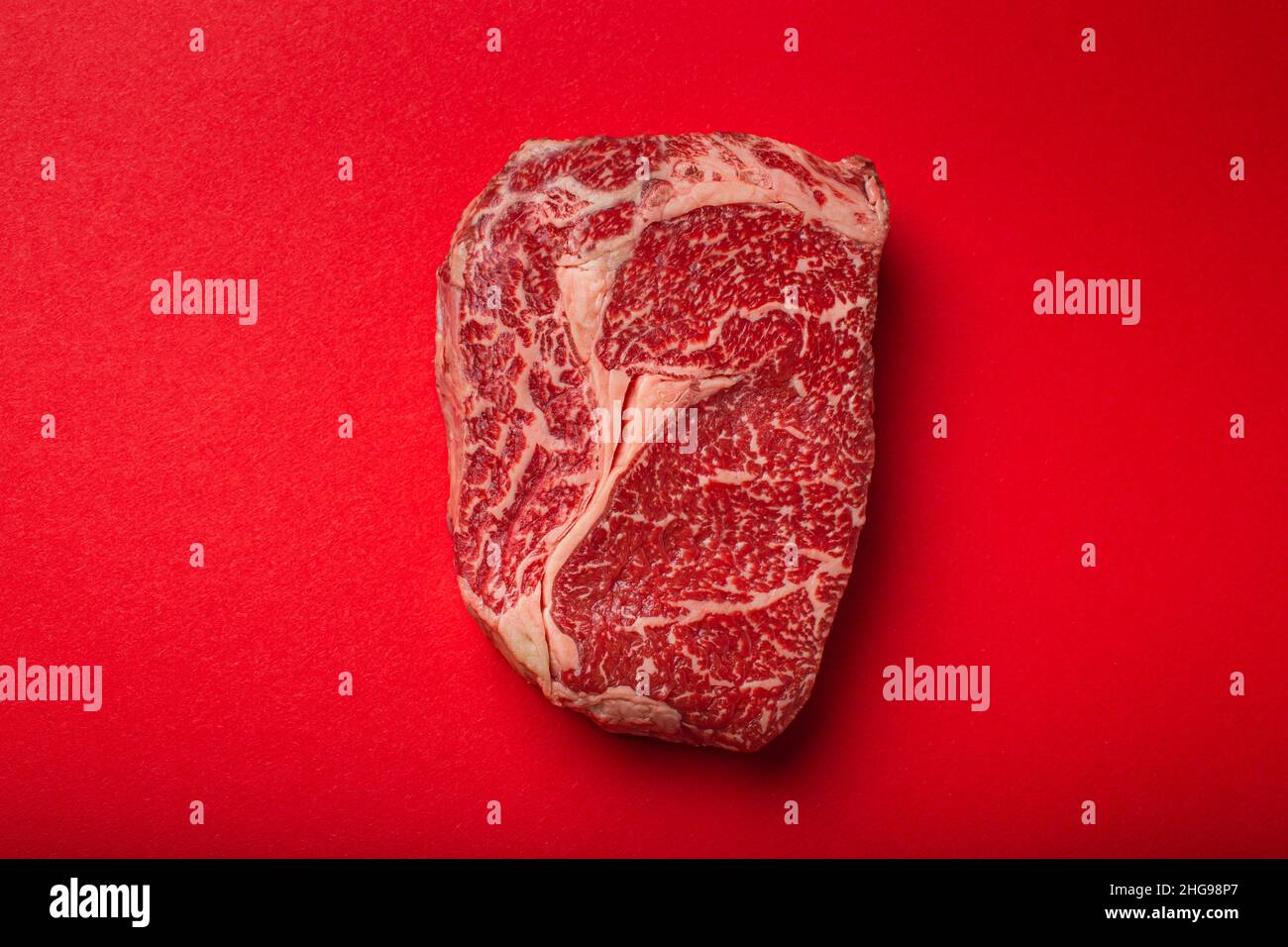 Raw meat beef prime cut steak Ribeye on clean red background from above, beefsteak concept banner minimalism Stock Photo