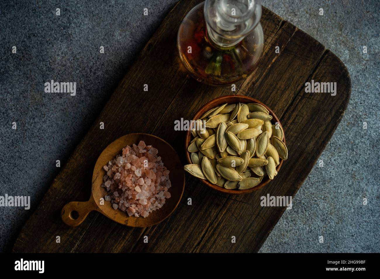 Overhead view of a bowl pumpkin seeds on a chopping board with pink