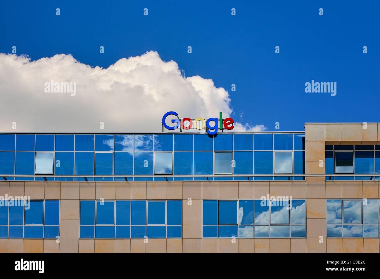 Wroclaw, Poland - Jun 6, 2021. Google sign or logo on top of the office building. Blue sky, daytime, big white cloud. Stock Photo