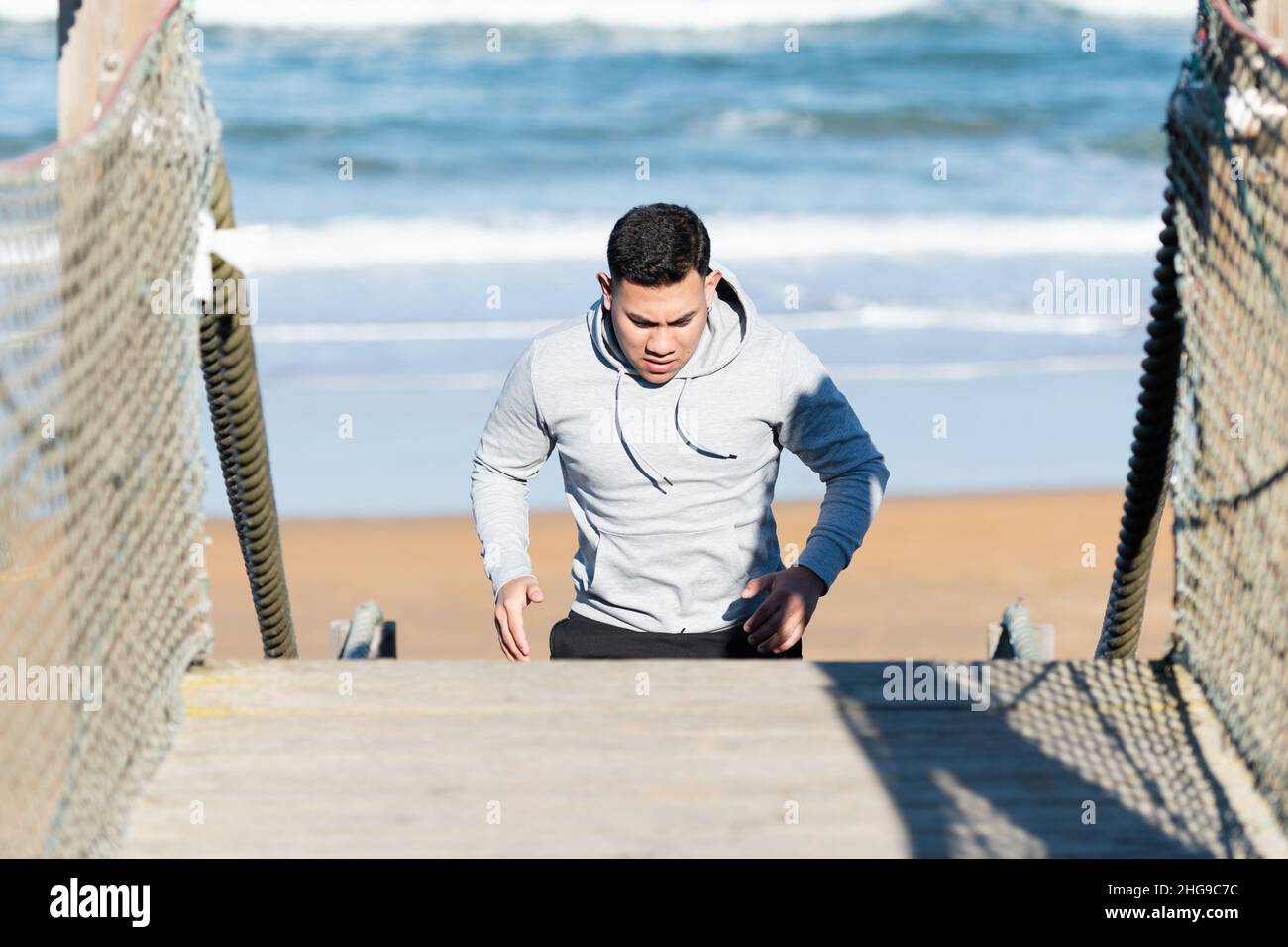 Young latin man running up on stairs from beach Stock Photo