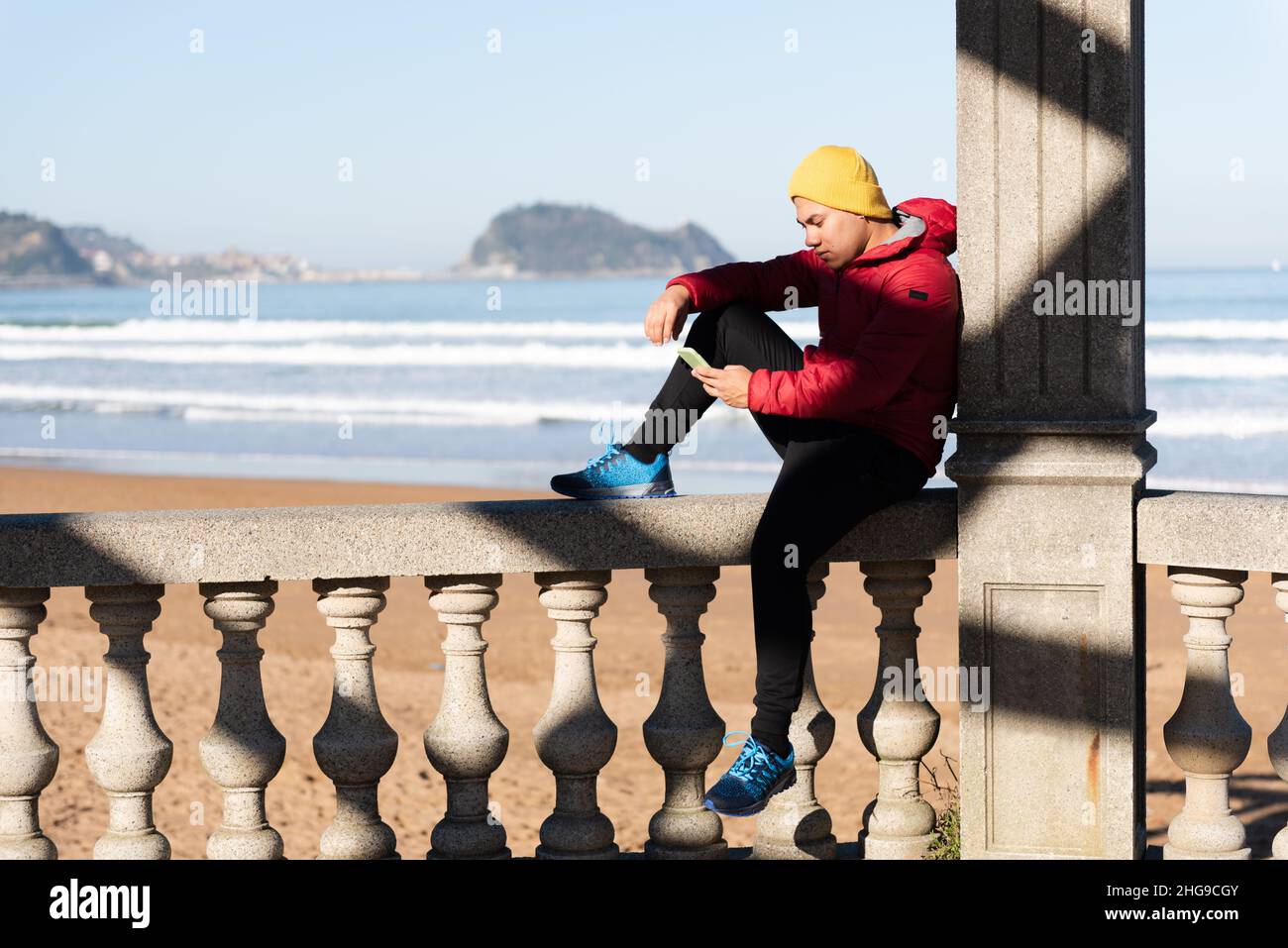 Young latin man using his phone and relaxing at seaside. Stock Photo