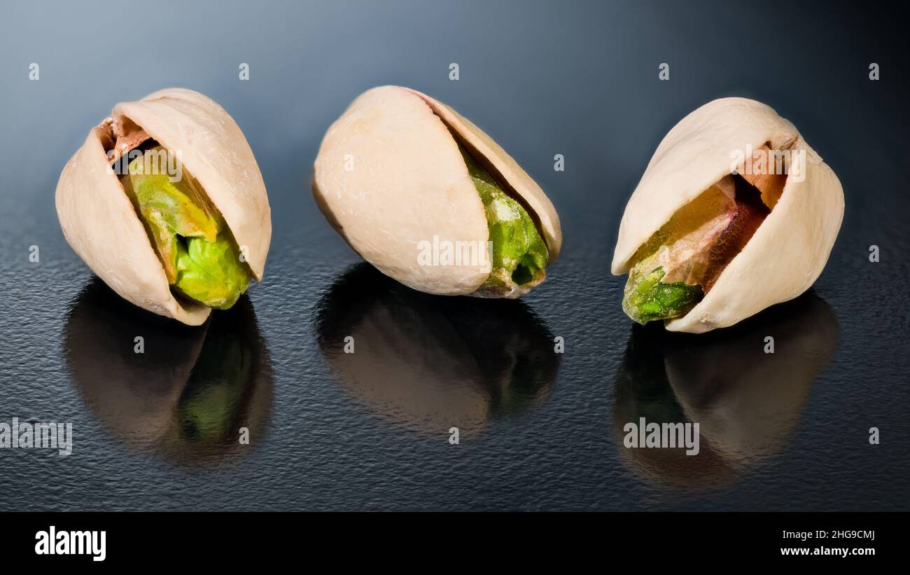Salty roasted pistachio nuts cores with reflection on shiny black