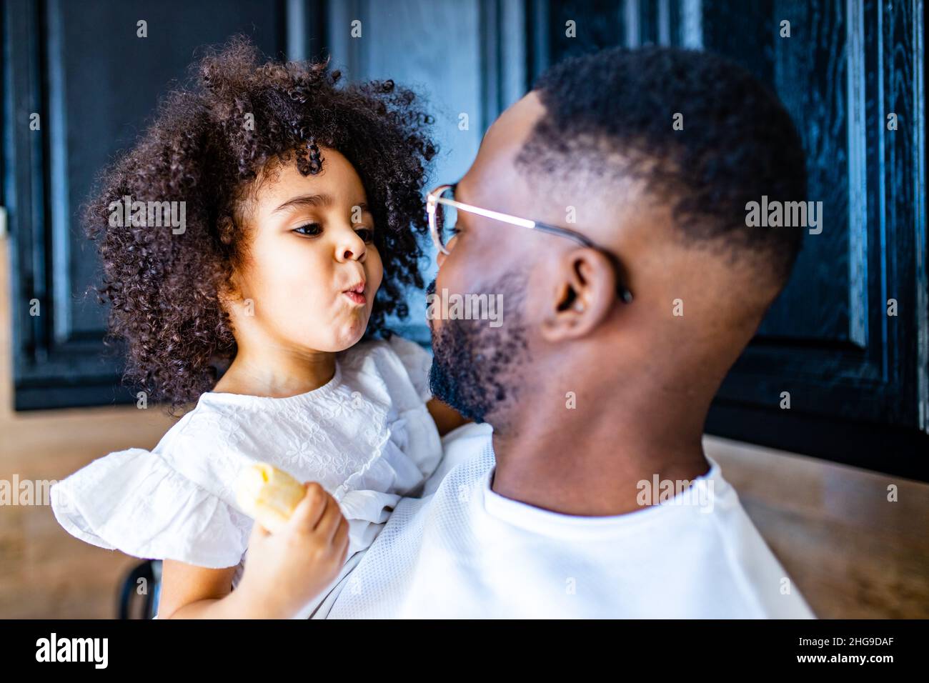 Portrait of a man hugging a little girl in home and eating a bananas Stock Photo