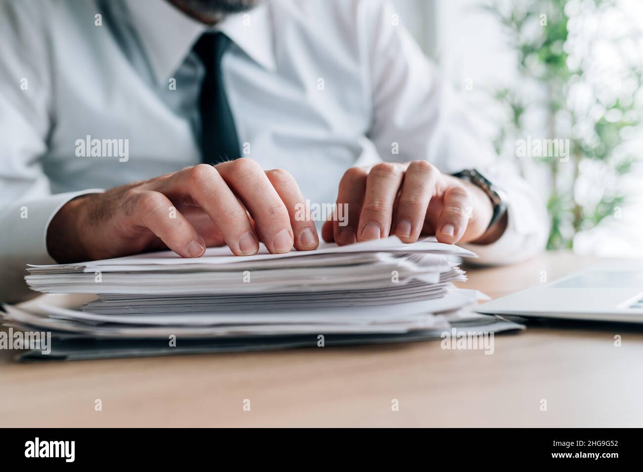 Paperwork workload, businessman with stack of reports for reviewing on office desk, selective focus Stock Photo