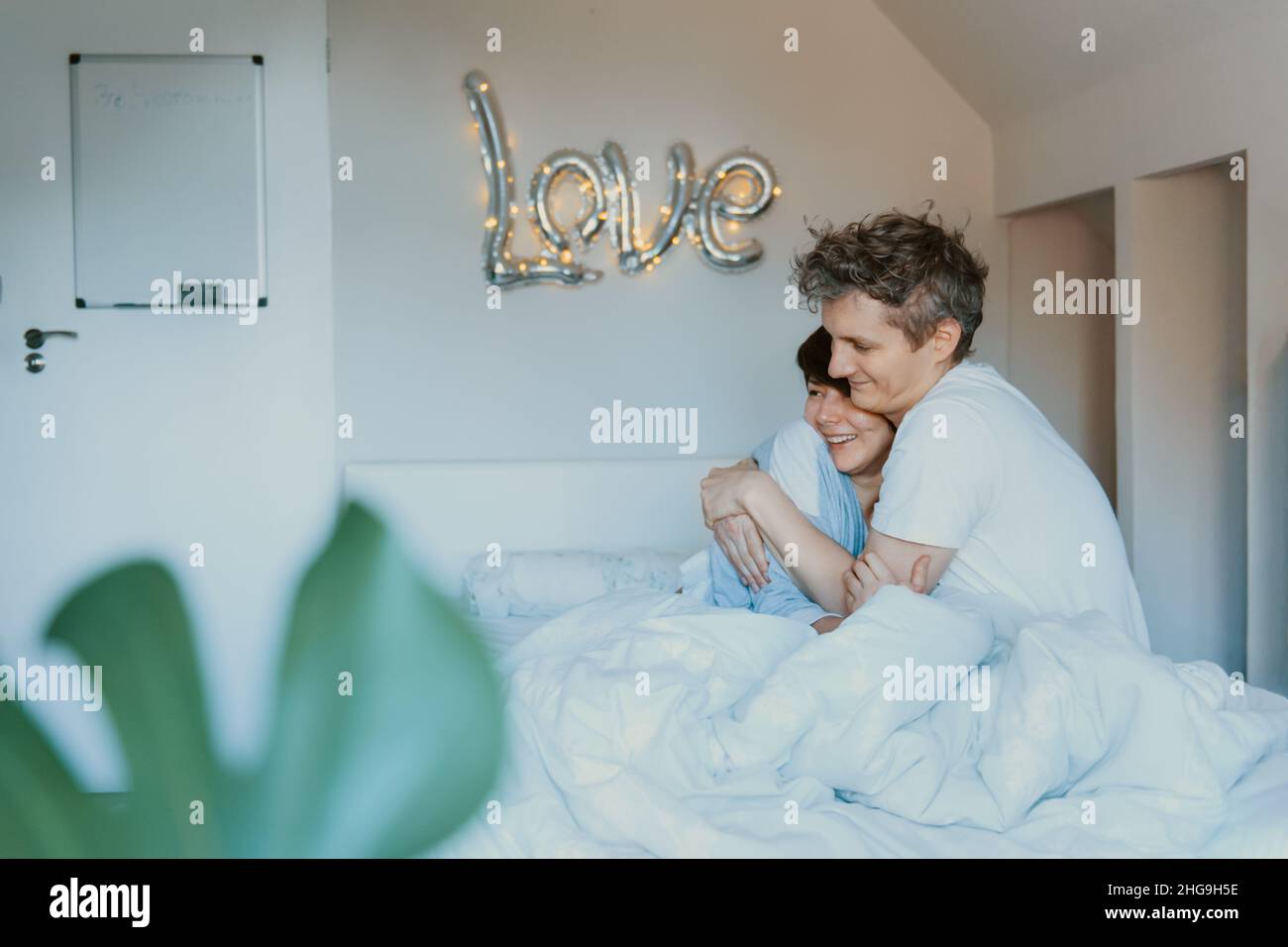 Loving couple in pajamas having fun in bed in the bedroom with word ...