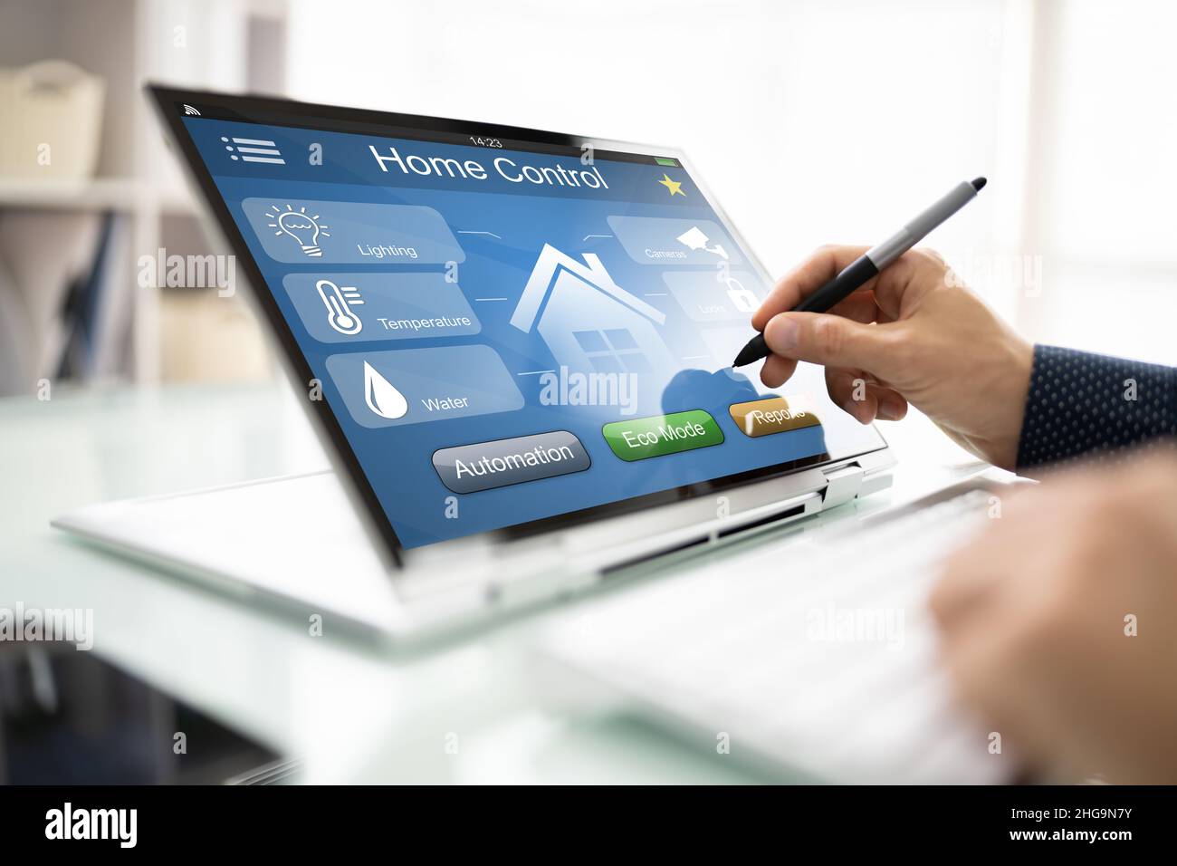 Person's Hand Using Home Control System On Digital Laptop Stock Photo