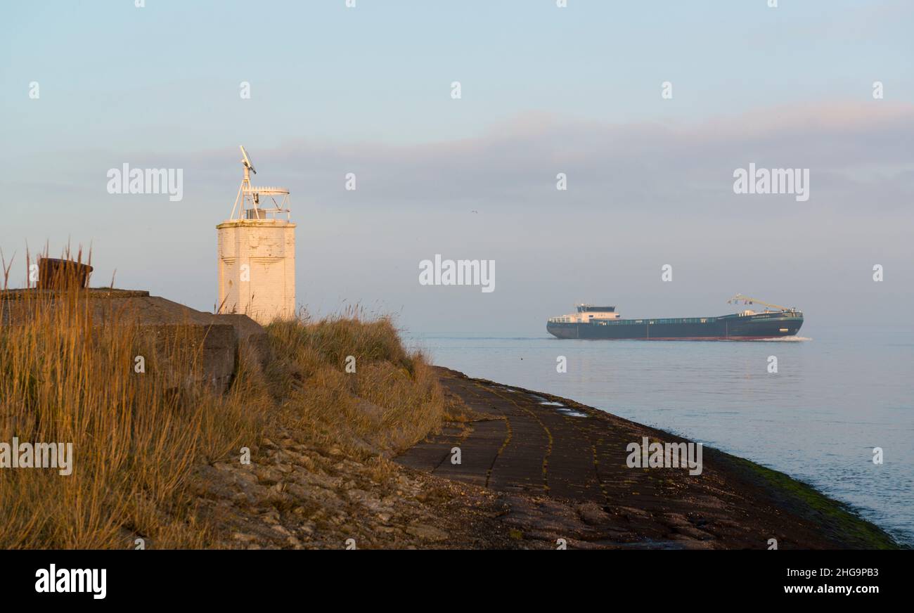 Inland vessel passing the harbor light of the village Hoedekenskerke on ...