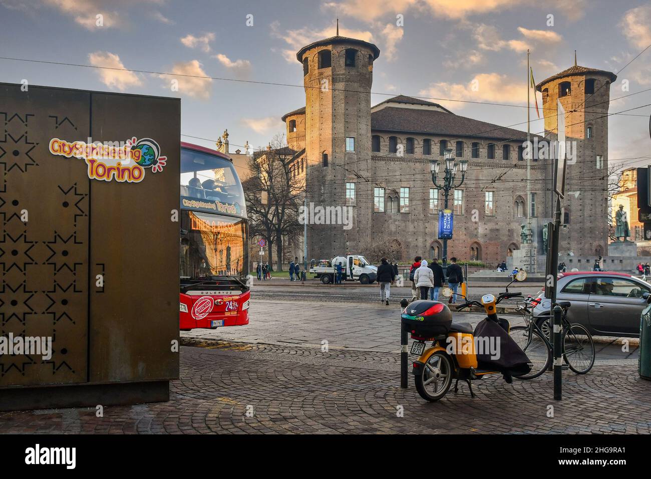 A City Sightseeing tourist bus in Piazza Castello square in front of the Casaforte of Acaja in the center of Turin at sunset, Piedmont, Italy Stock Photo