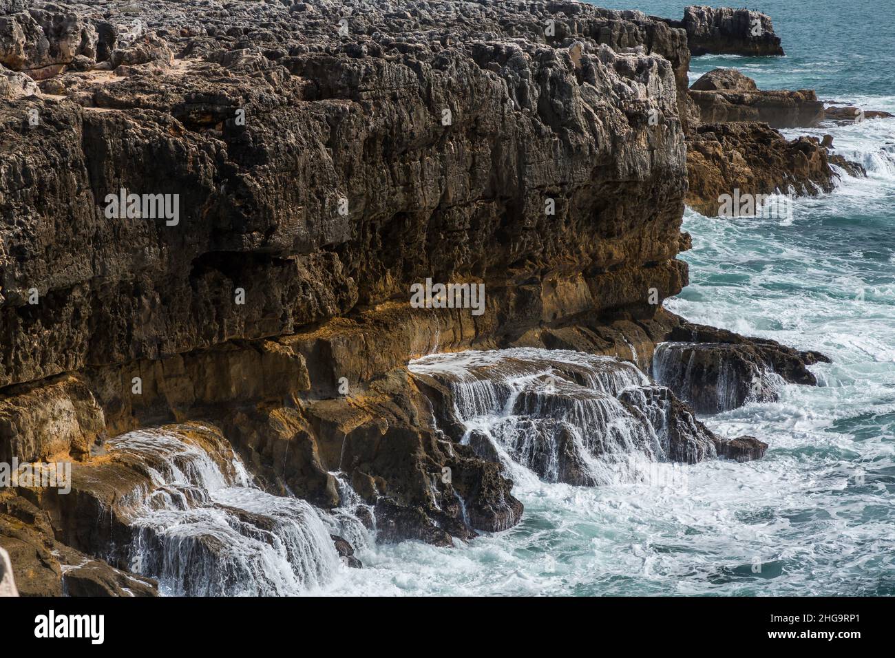 The pounding surf drains its force against the steep, monstrous seaside cliffs, Portugal Stock Photo