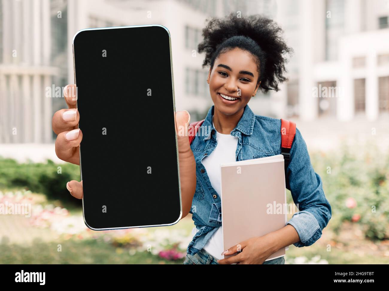 Mobile Mockup. Cheerful Black Female Student Demonstrating Big Blank Smartphone At Camera Stock Photo