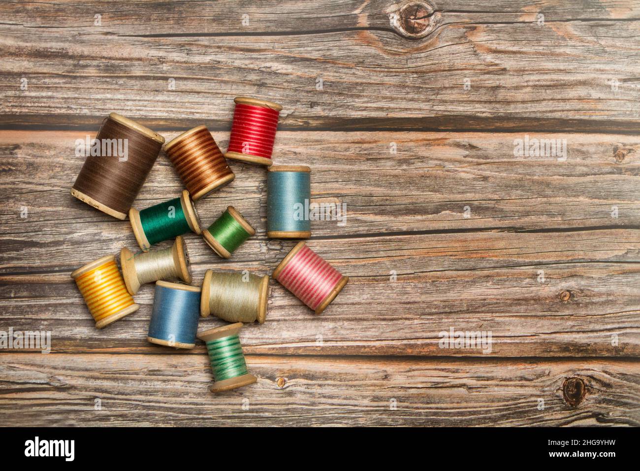 Colored thread spools on a wooden background with copy space Stock Photo