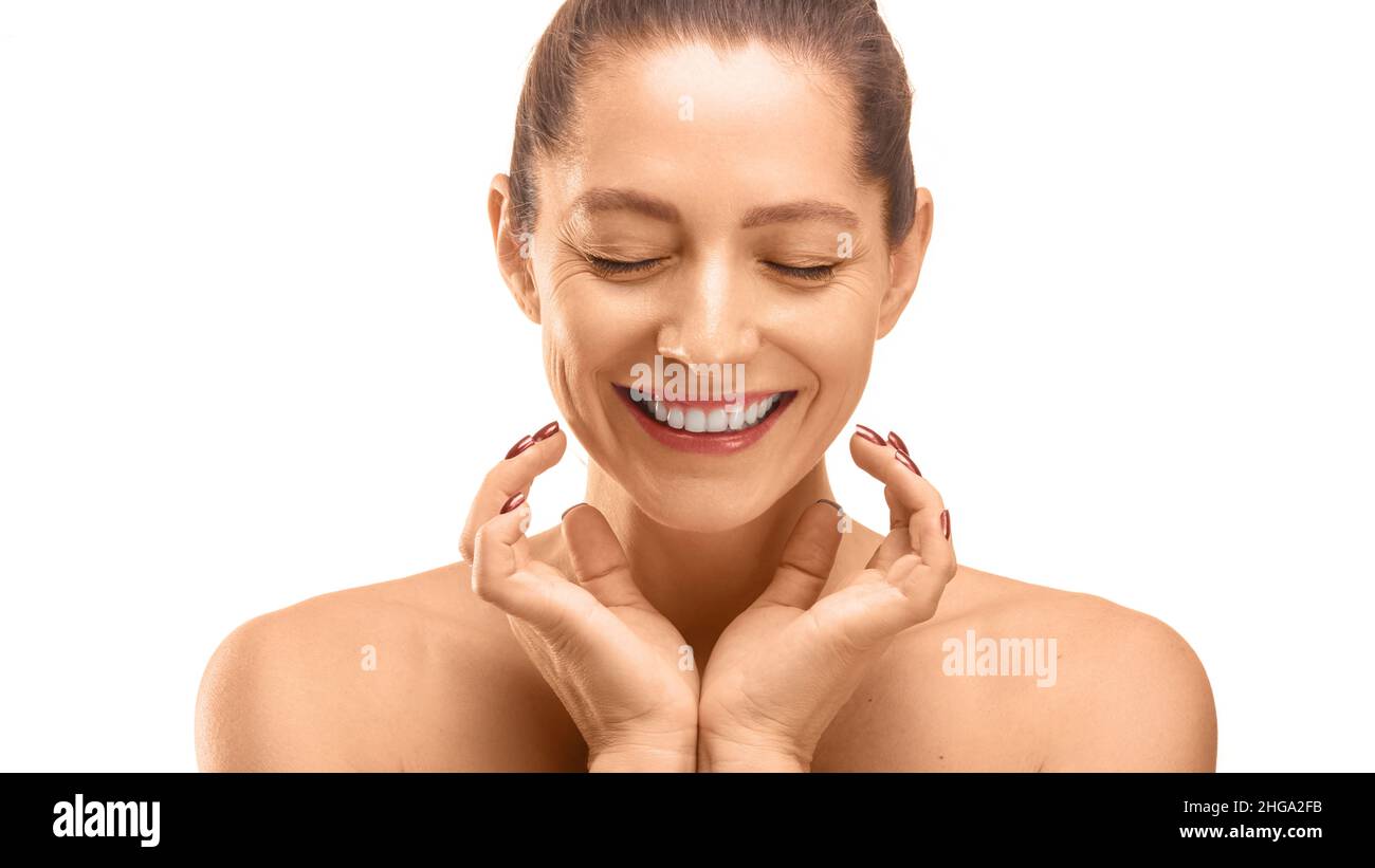Portrait of a 40 years old woman with closed eyes touching her skin. Skin care concept. Isolated on white Stock Photo