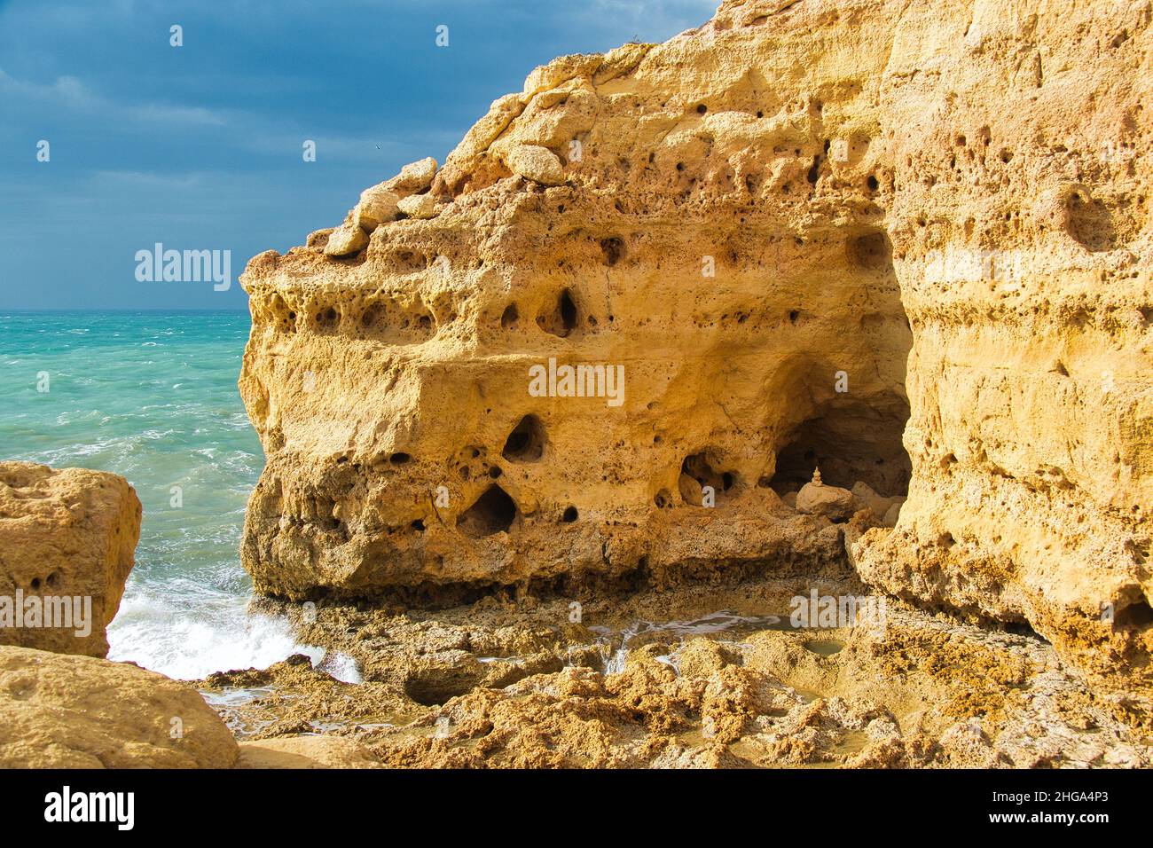 Towering limestone cliffs with lots of caves rise up from a stormy sea. Algar Seco, Carvoeiro, Algarve, Portugal Stock Photo