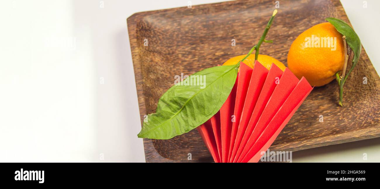 Chinese New Year, composition with tangerines, funny origami made of red paper on a dark wooden plate on a white background, space for text on the lef Stock Photo