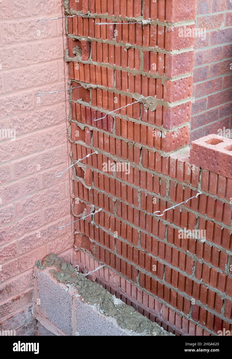 A cavity wall under construction showing metal brick or wall ties in position Stock Photo
