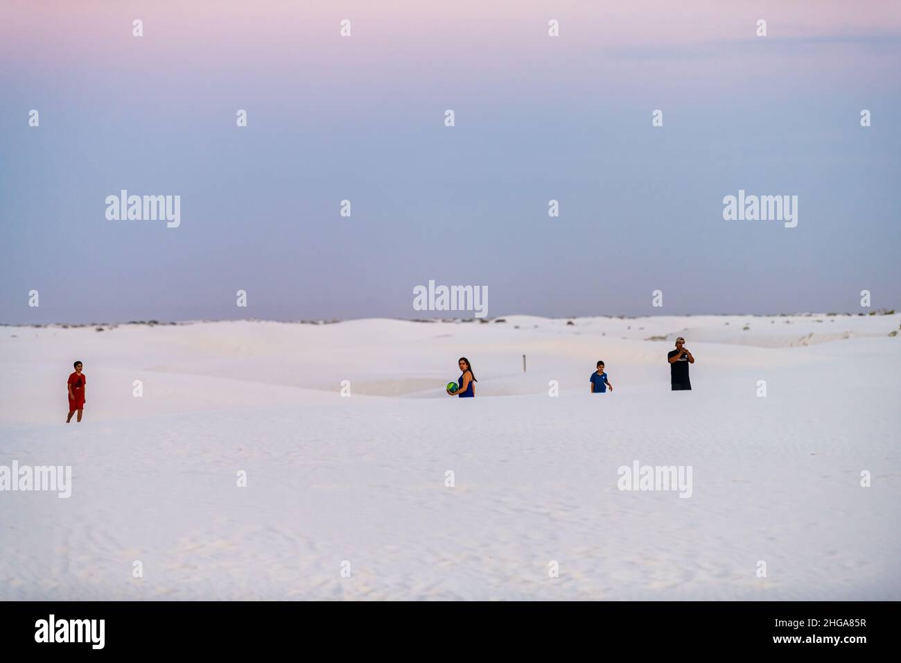 Alamogordo, USA - June 9, 2019: White sand dunes in New Mexico with group of people in background during pastel sunset twilight purple pink blue sky Stock Photo