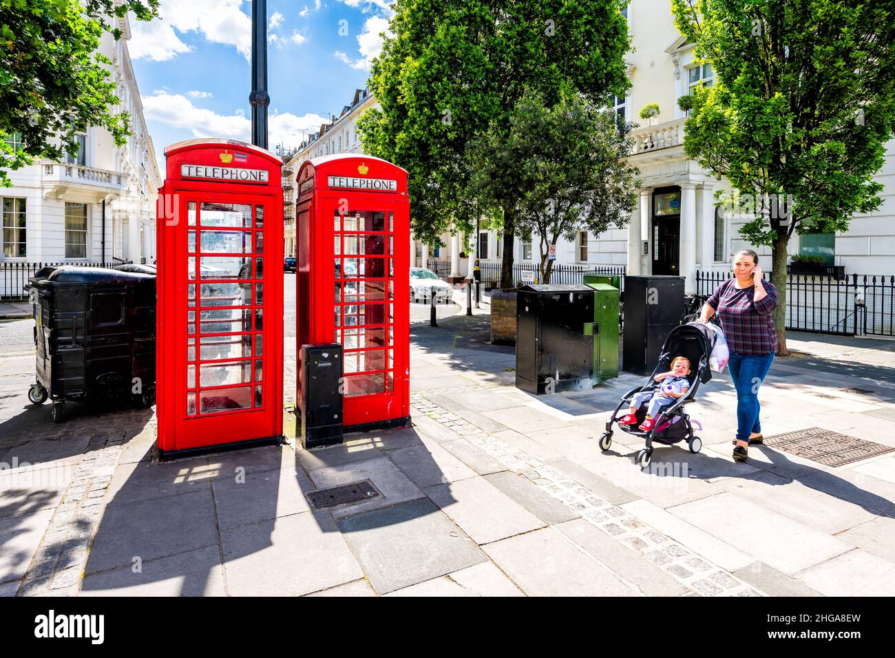 London, UK - June 21, 2018: Street sidewalk road pavement in Pimlico Westminster district area with red telephone booth and candid woman pedestrian wa Stock Photo