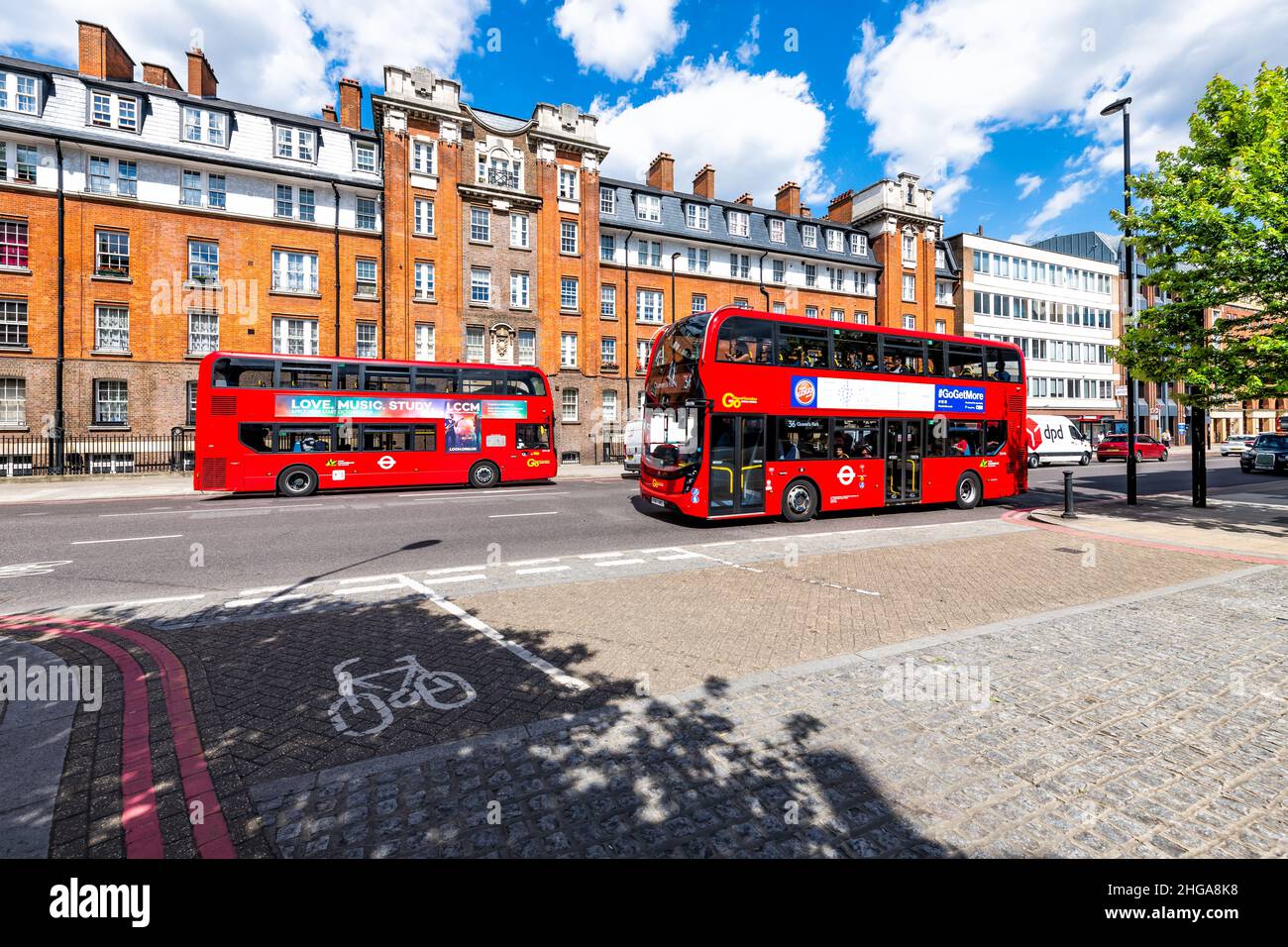 London, UK - June 21, 2018: Two red double decker buses on street in center of downtown city with advertisement sign for love music study and Pizza Go Stock Photo