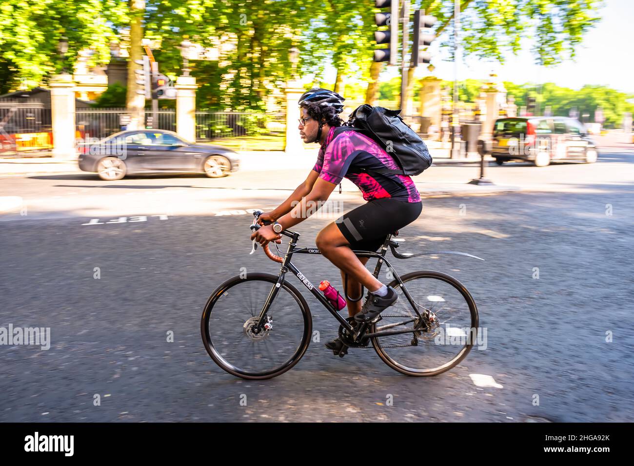 London, UK - June 22, 2018: Side view panning of candid local man riding bicycle bike sport in traffic on street road in London with blurred motion ac Stock Photo