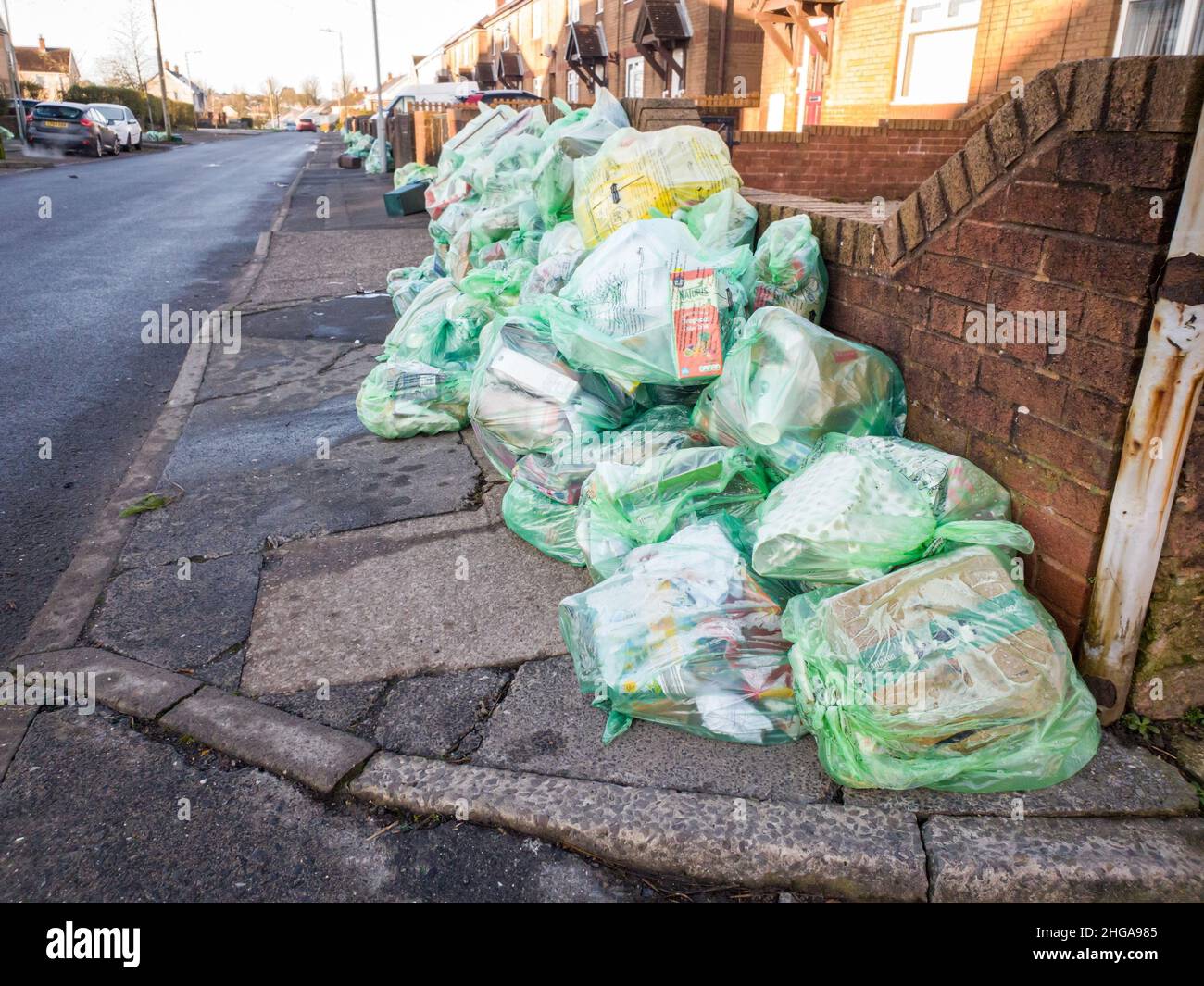 Lots of full recycling bags in a residential area street, ready for collection by the waste collectors, pile of garbage bags on sidewalk. Swansea, Wales, UK - January 17, 20222 Stock Photo