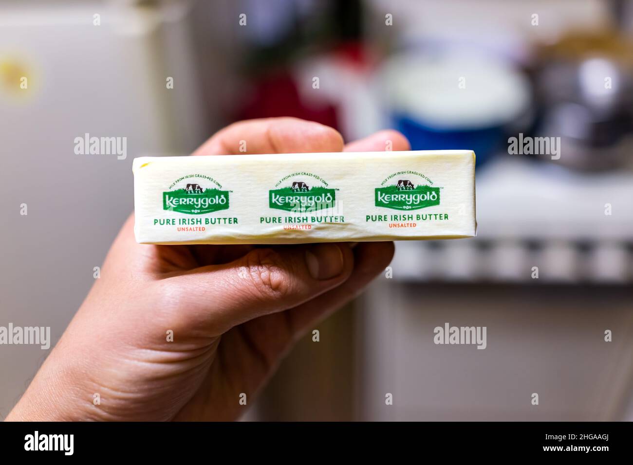 Banner Elk, USA - June 4, 2021: Hand holding storebought small 4 ounce stick of unsalted butter with sign label for Kerrygold grass-fed pure Irish bra Stock Photo