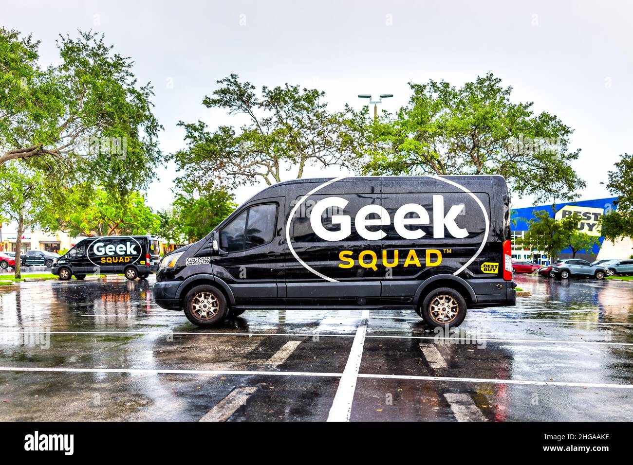 Miami, USA - July 12, 2021: Sign advertisement for Best Buy store on exterior building facade and Geek Squad repair van truck in parking lot in Florid Stock Photo