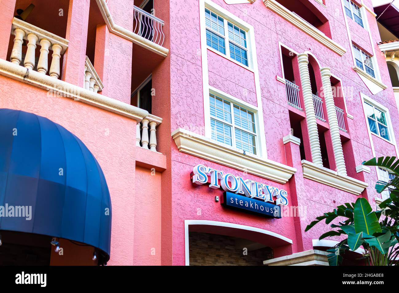 Naples, USA - September 13, 2021: Naples, Florida Bayfront condo colorful pink coral Spanish architecture building with sign for Stoney's restaurant s Stock Photo