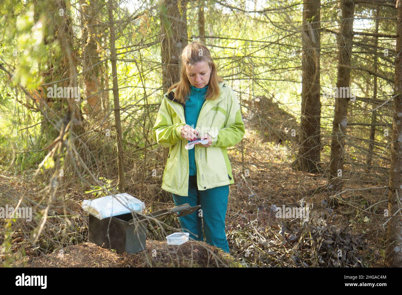 A woman geocaching. Women in woods find geocache container.  Stock Photo
