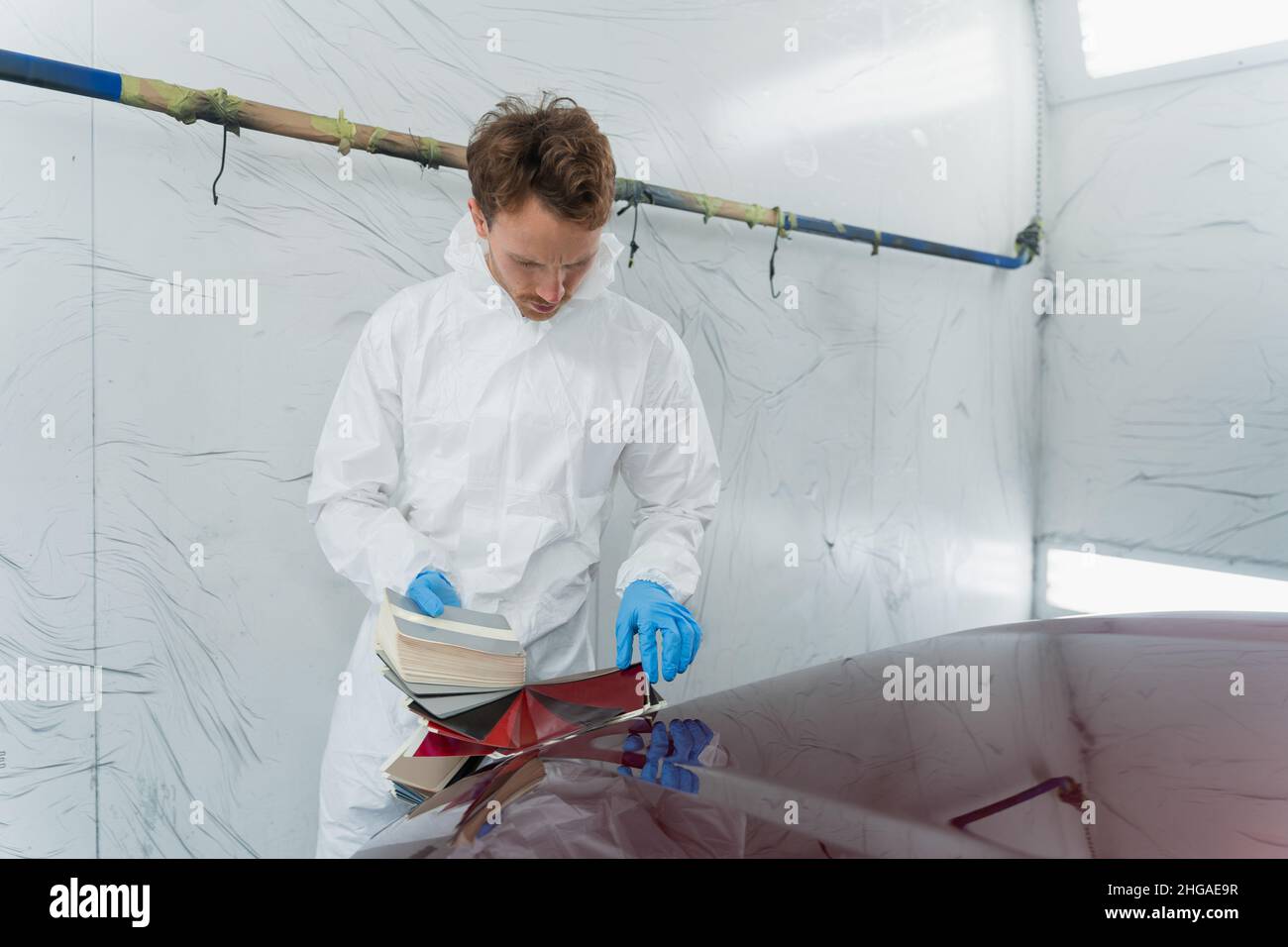 Man chooses car paint shade using samples. Auto colorist in vehicle