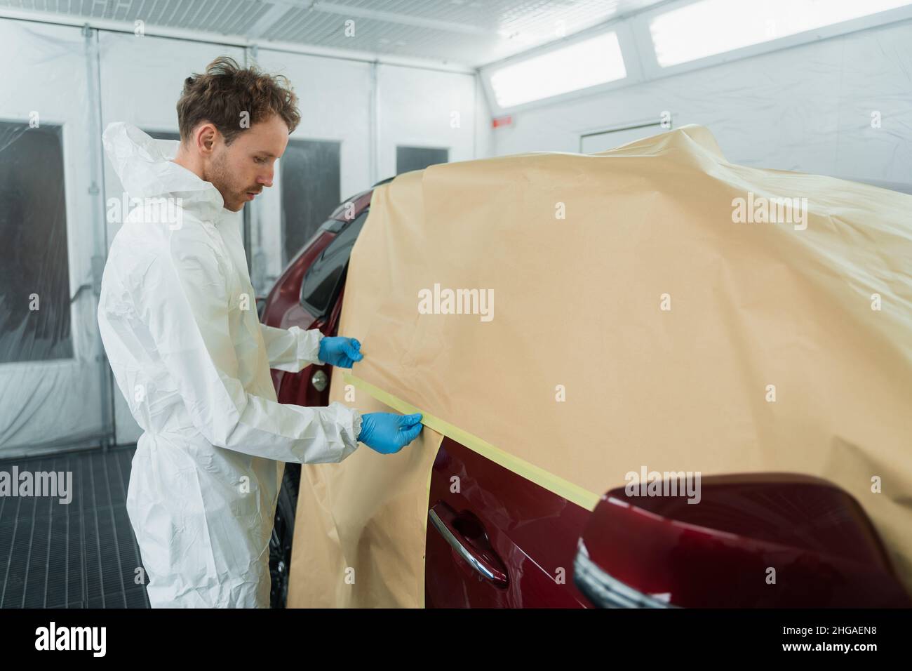 Auto painter masking car with paper before painting or polishing in