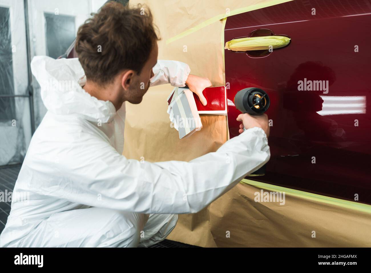 Colorist man compare color sample with car paint using special lamp ...