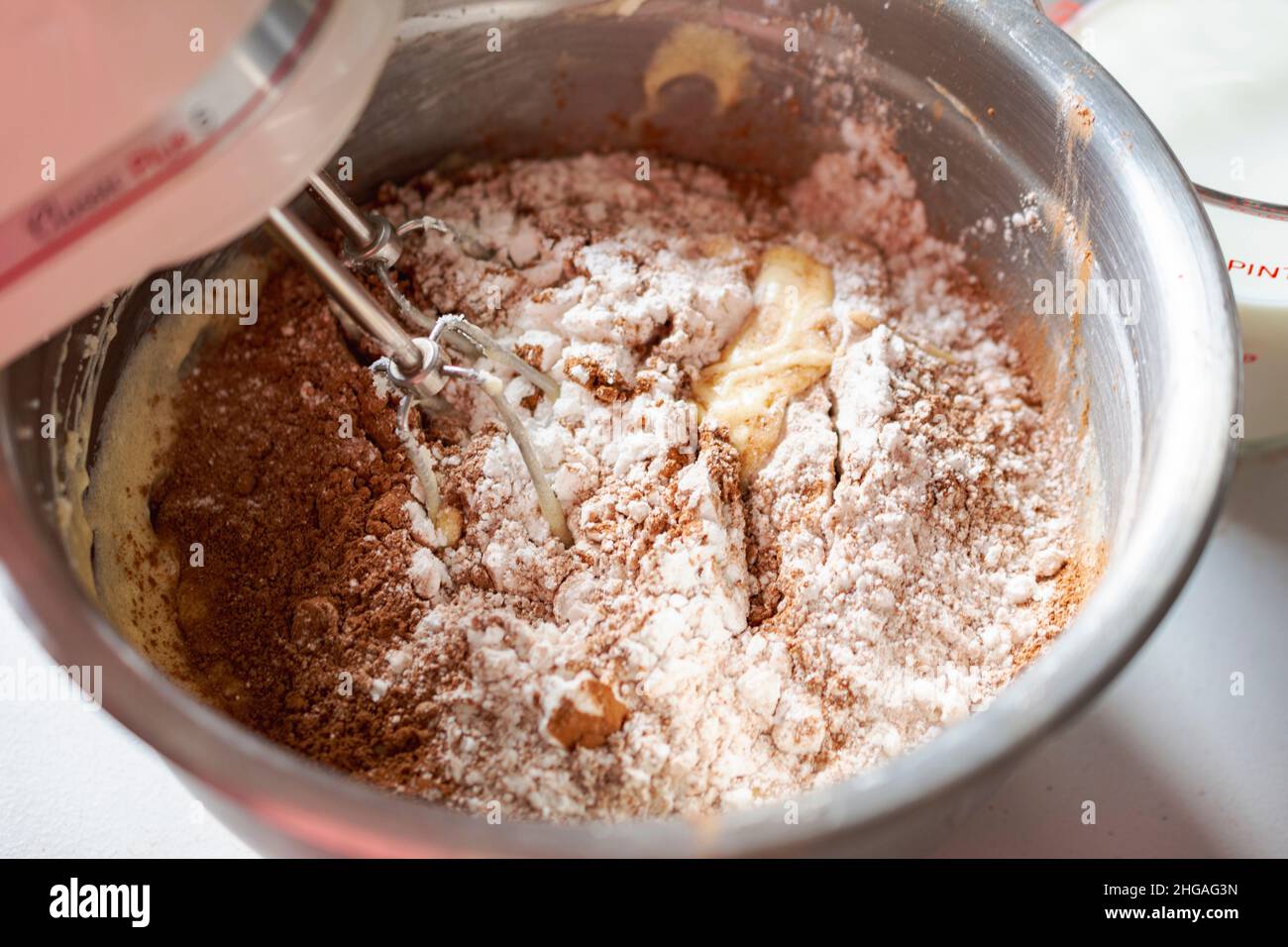 Making of a chocolate cake:  Adding dry ingredients.  Mixer beaters stationary. Stock Photo