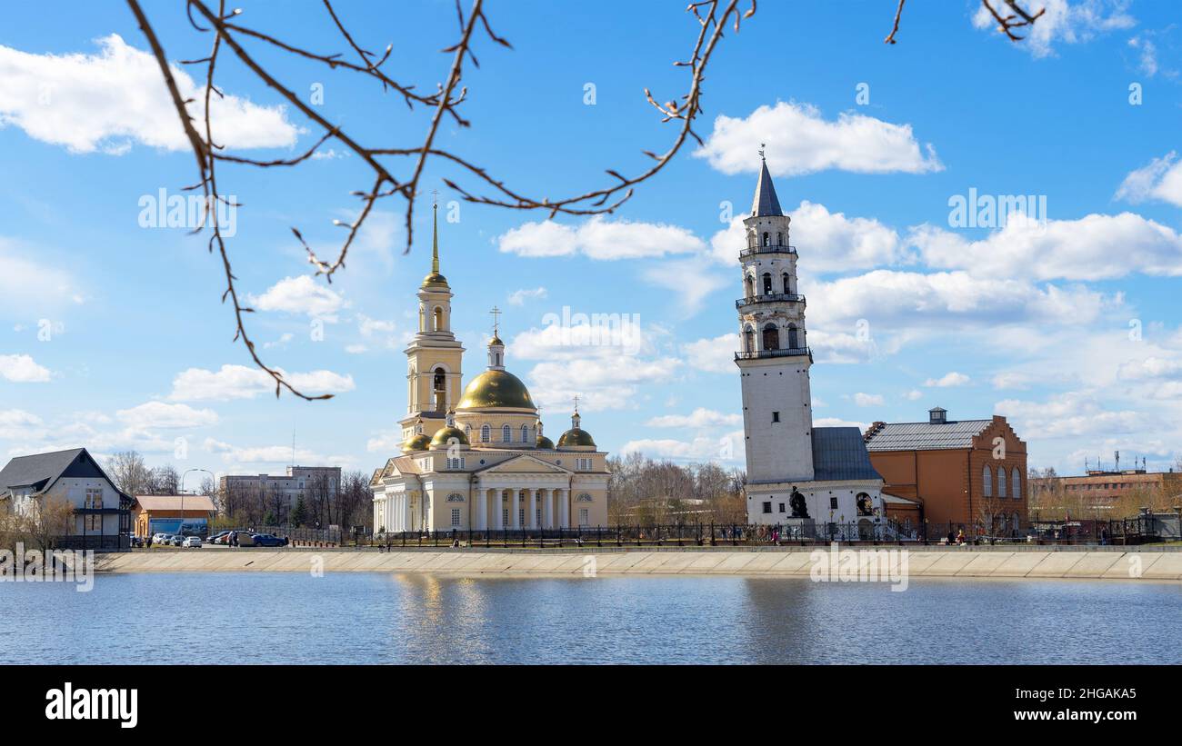 Leaning Tower of Nevyansk and Old Believers' church (domed) in spring day on the shore of the pond in Sverdlovsk Oblast, Russia. Stock Photo