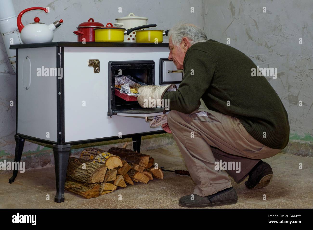 mature man using a traditional wood burning stove to cook a roast