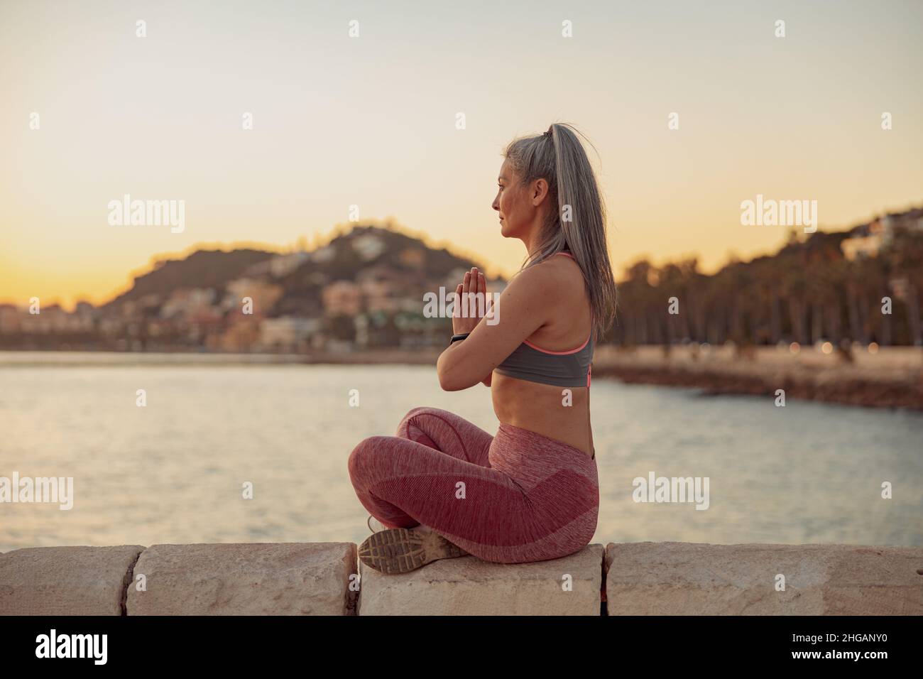 Sporty woman meditating in lotus position at seaside Stock Photo - Alamy