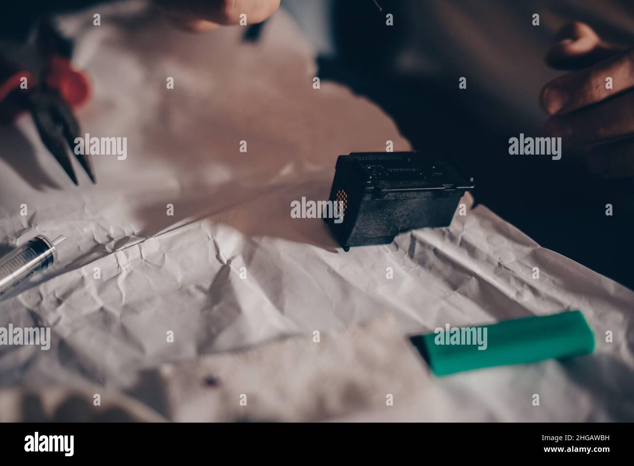 Male hands refill printer cartridge. The guy makes holes in the cartridge and pours ink through