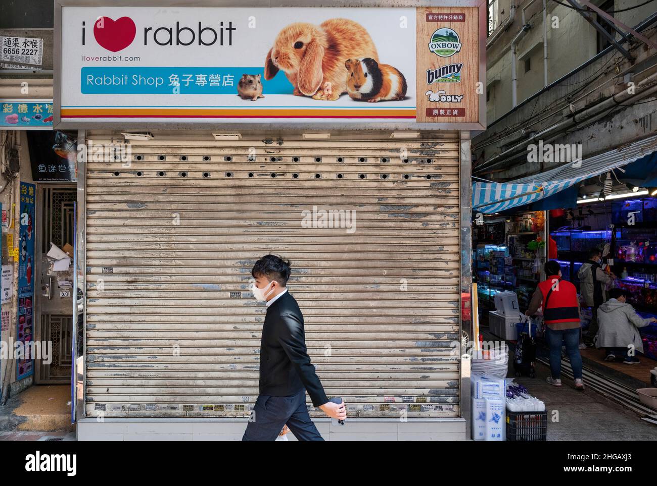 A pedestrian walks past a closed pet shop which sells hamsters in Hong