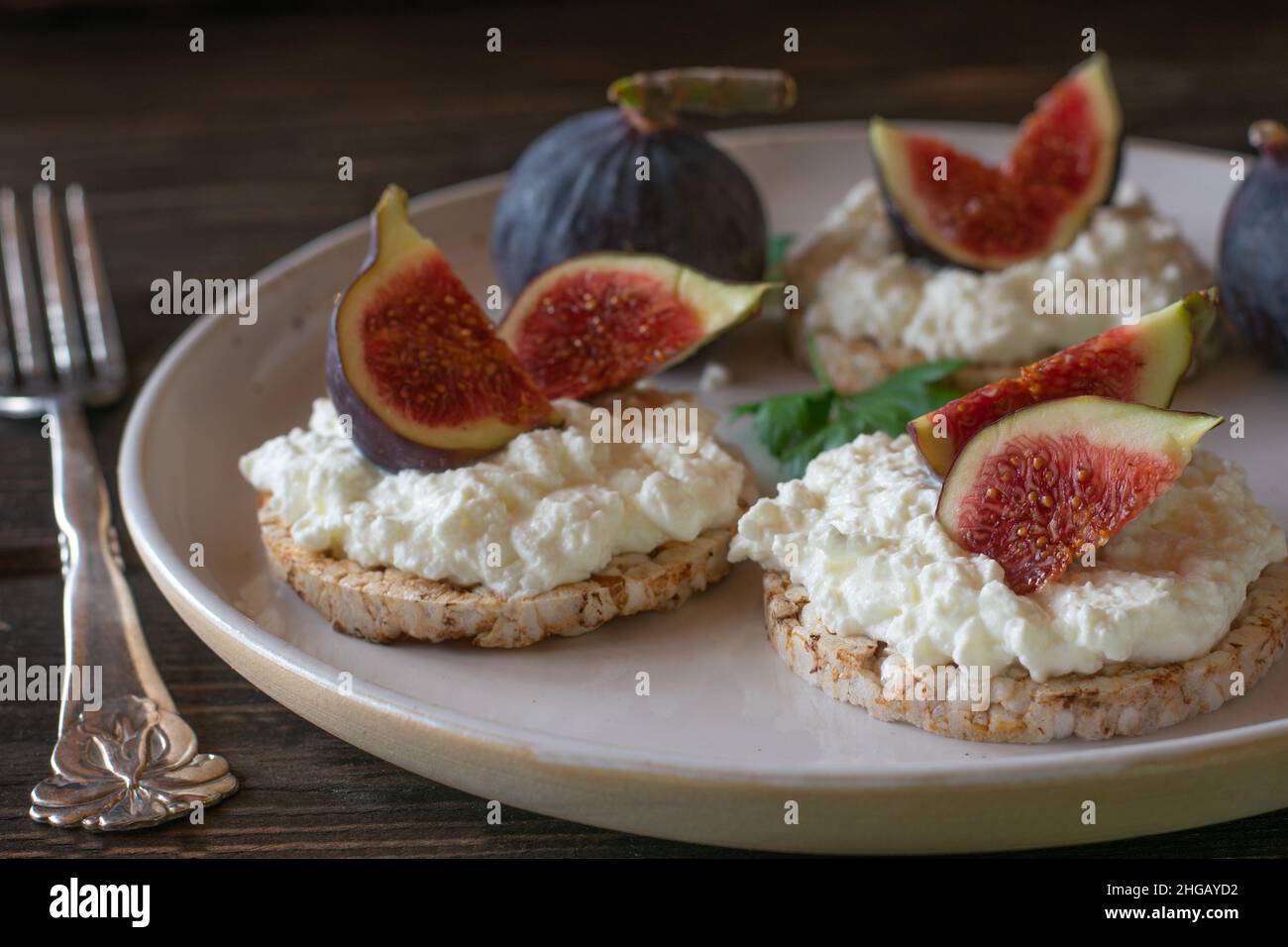 Healthy breakfast plate for diet or dieting with gluten free brown rice cracker topped with cottage cheese and fresh figs Stock Photo