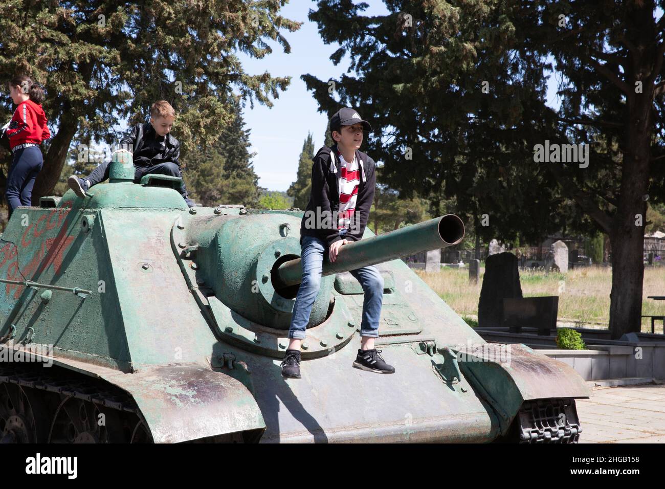 Kukia cemetery, children playing on old Soviet tank at the memorial for the soldiers who died in the war, Tbilisi, Tbilisi, Georgia Stock Photo