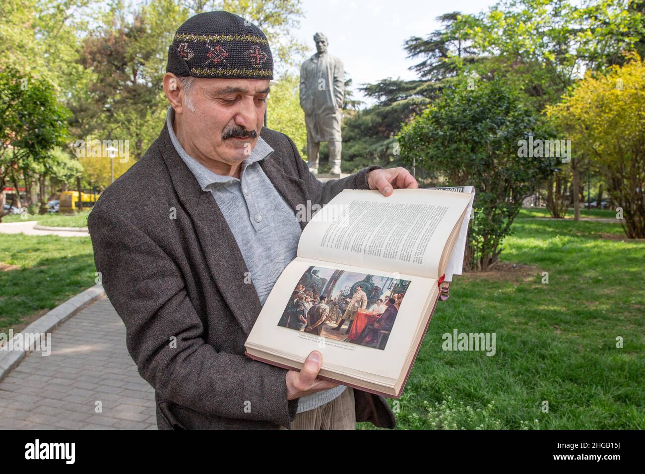 A man shows a book with pictures of Stalin, Tbilisi, Georgia, in front of the Mayakovski statue Stock Photo