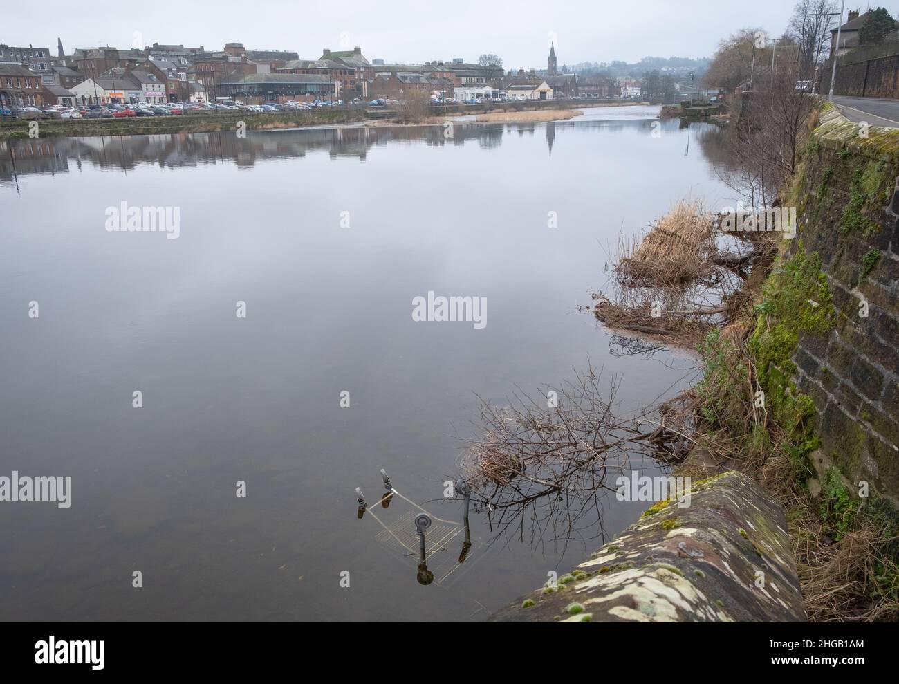 A view of the River Nith in Dumfries, Scotland with a shopping trolley and debris in the foreground. Stock Photo