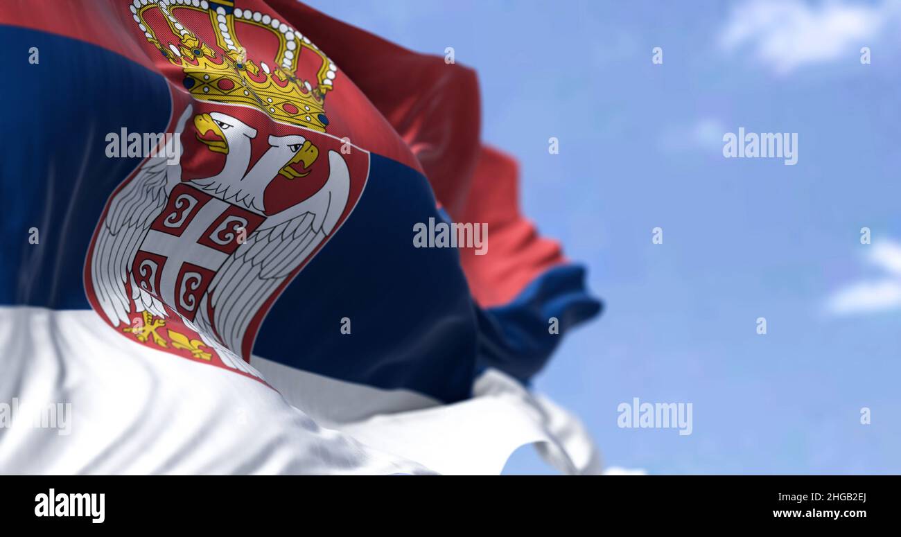 Detail of the national flag of Serbia waving in the wind on a clear day. Democracy and politics. European country. Selective focus. Stock Photo